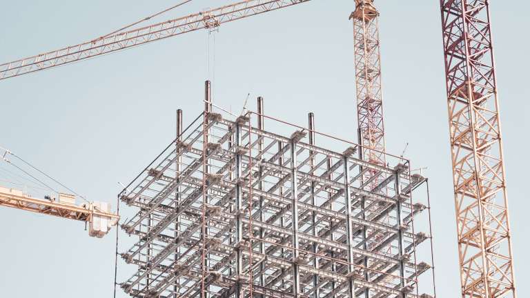 Cranes tower over the skeleton structure of a building under construction