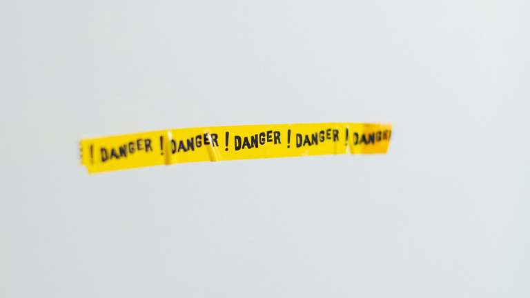 yellow tape reading danger is stuck on a white wall