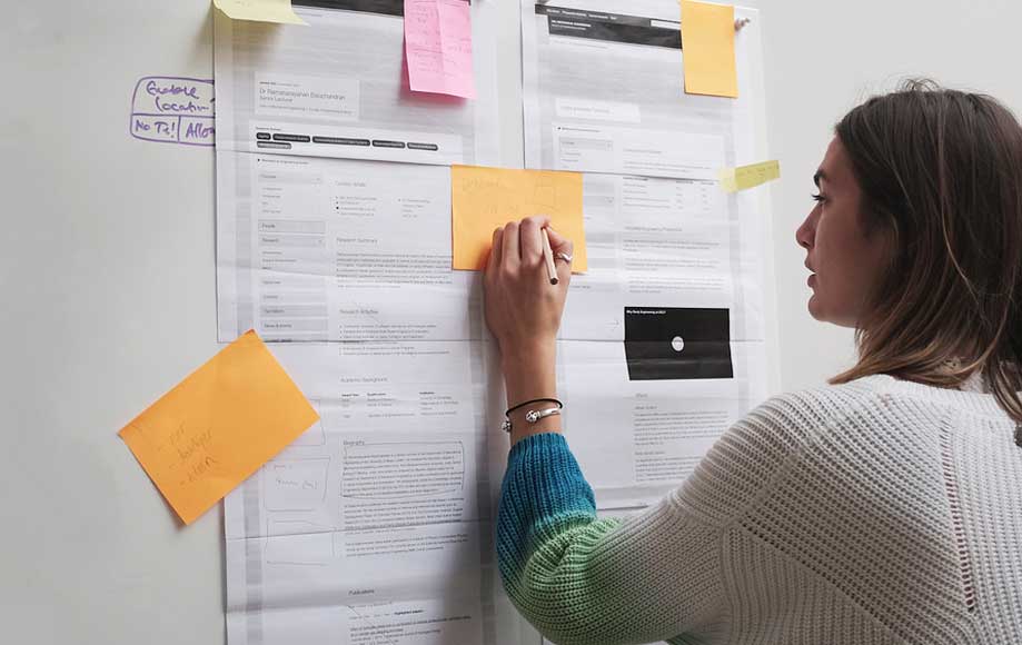 A person writes on a wall of notes as part of a discovery phase workshop