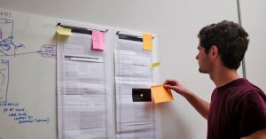 A person sticks post it notes to a wall during a discovery phase application design post it