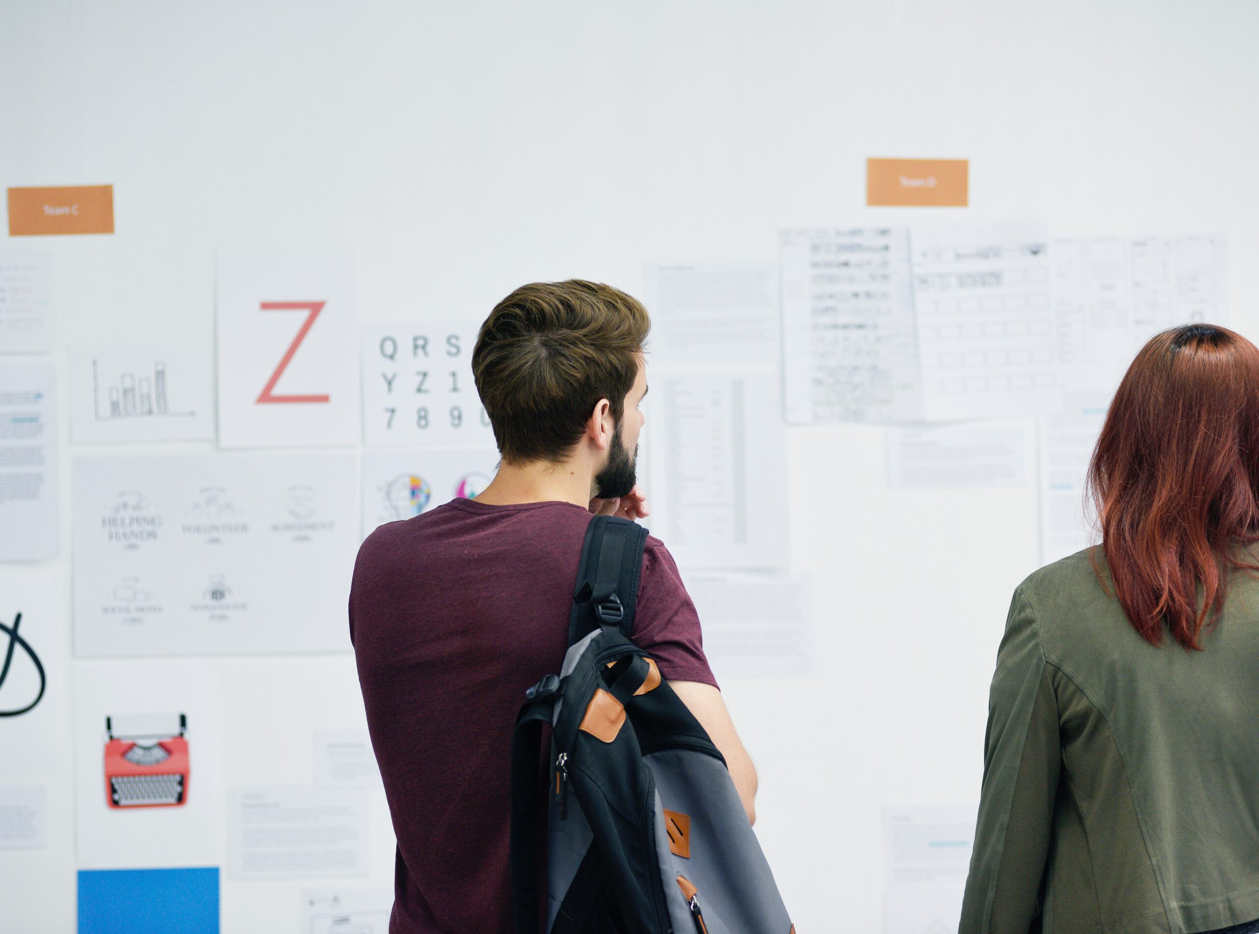 A member of a development team looks at a website mockup on a wall