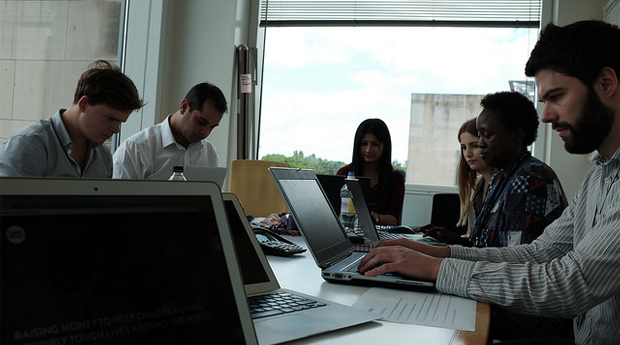 A young group of people work on laptops around a table