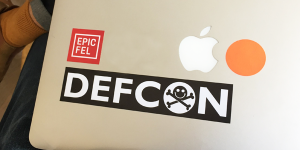 A man displays the stickers on the lid of his Apple laptop