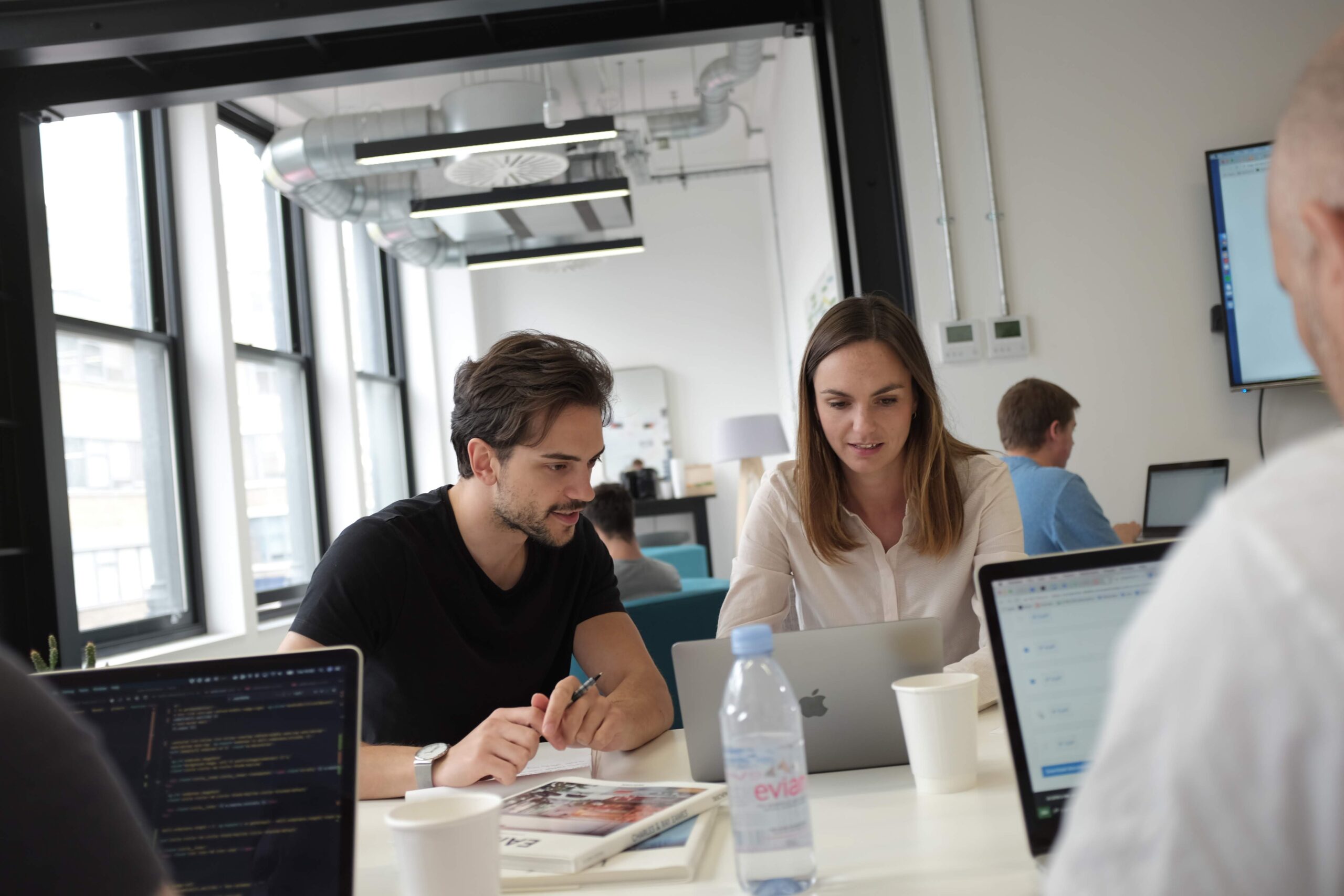 Two people collaborate in front of a computer in our office