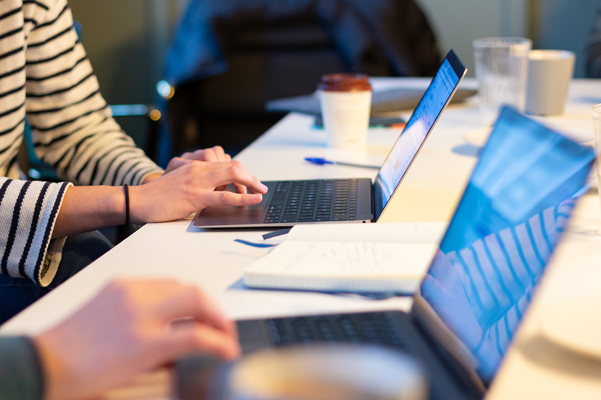 A digital development team works on laptops at a table