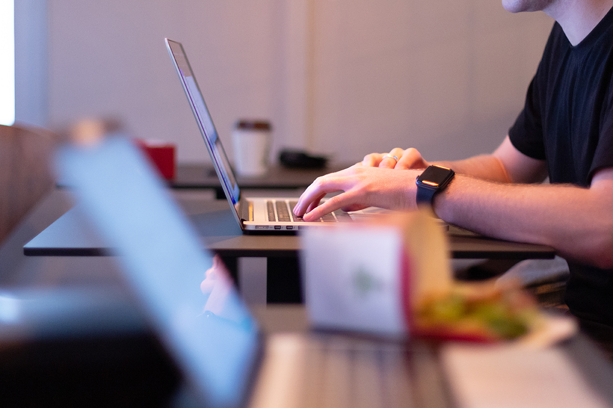 A person types on a laptop set on a table