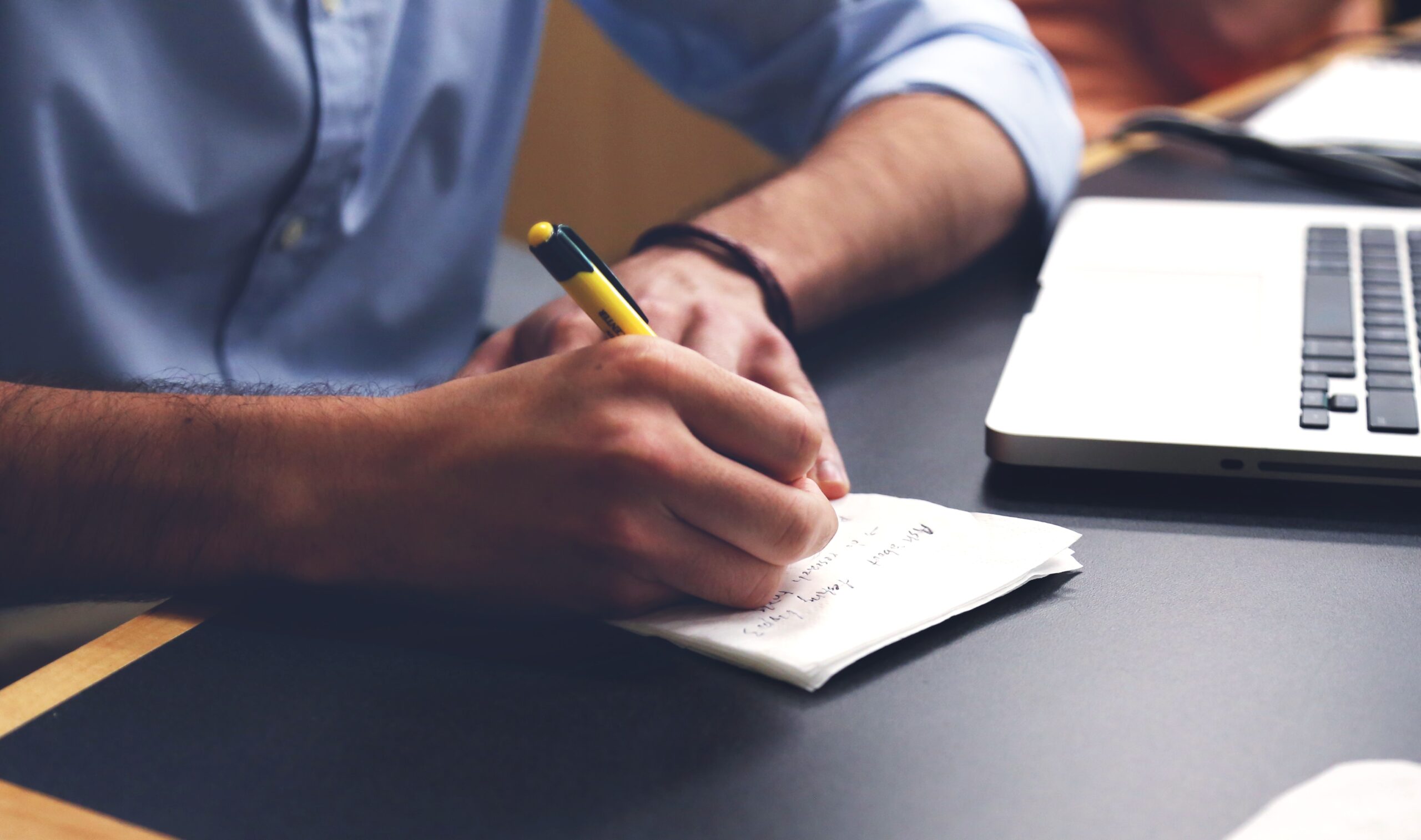 Man writing a project brief with pen and paper