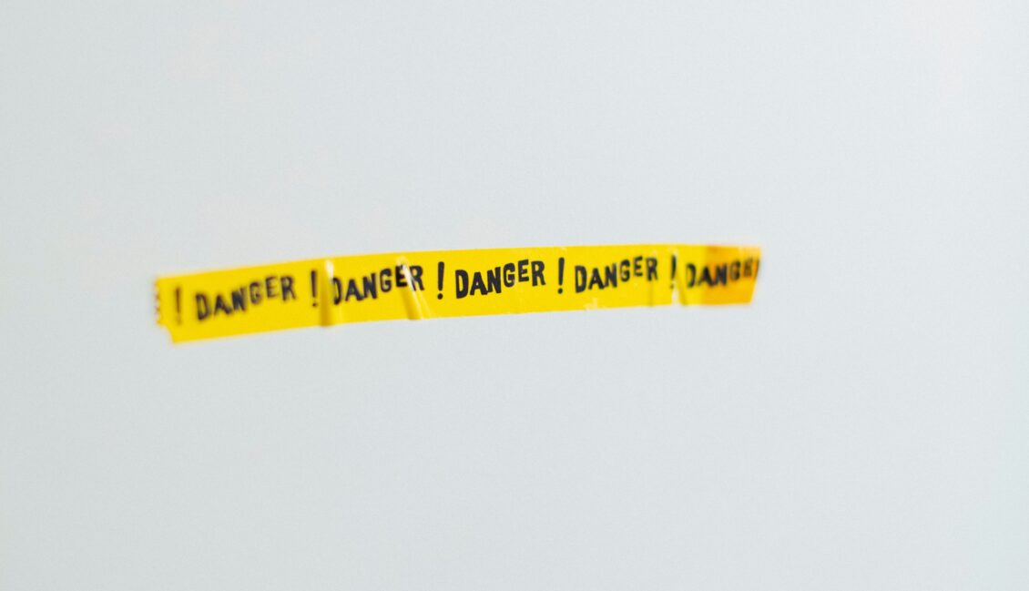yellow tape reading danger is stuck on a white wall
