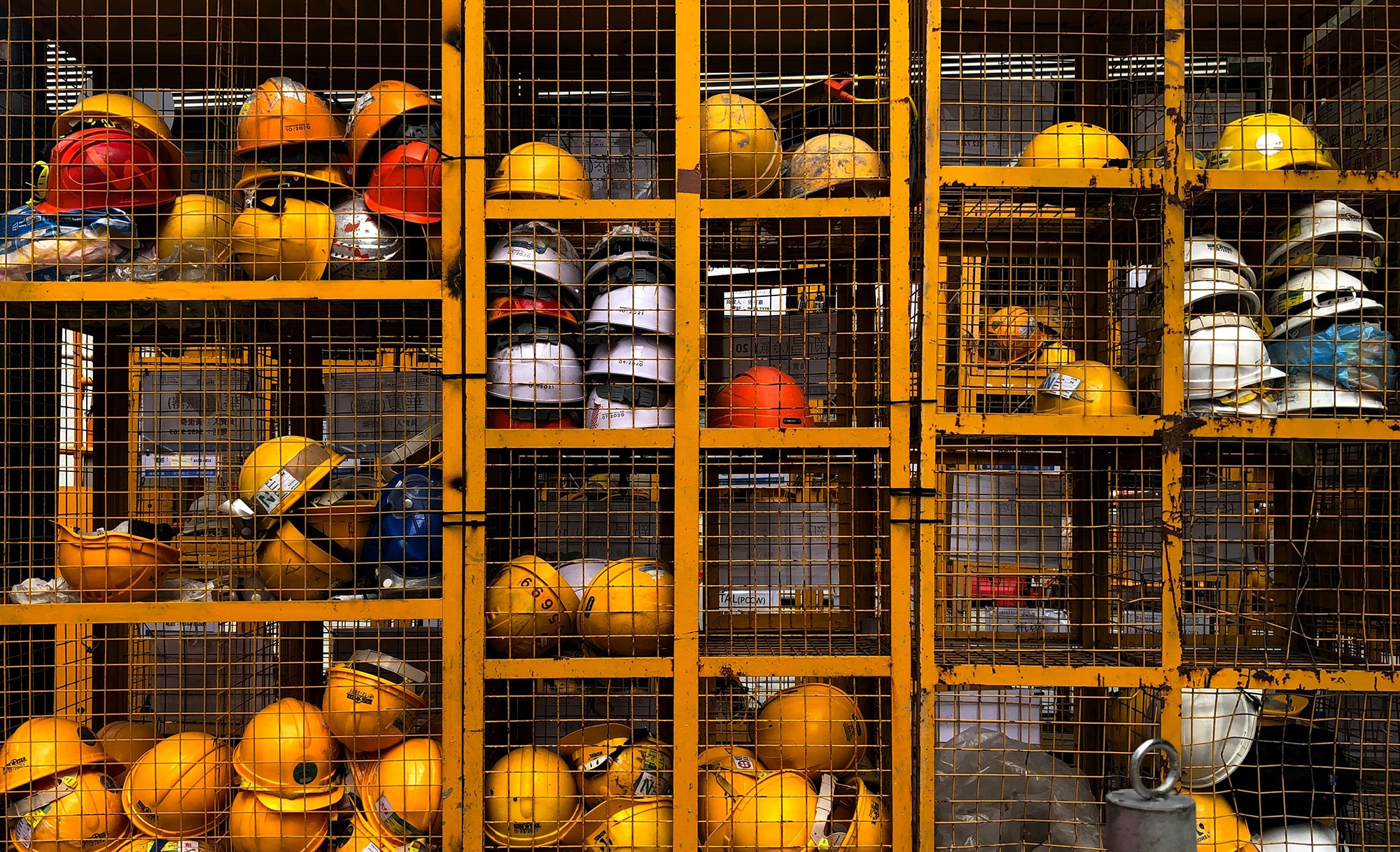 numerous hard construction hats sit on some shelves