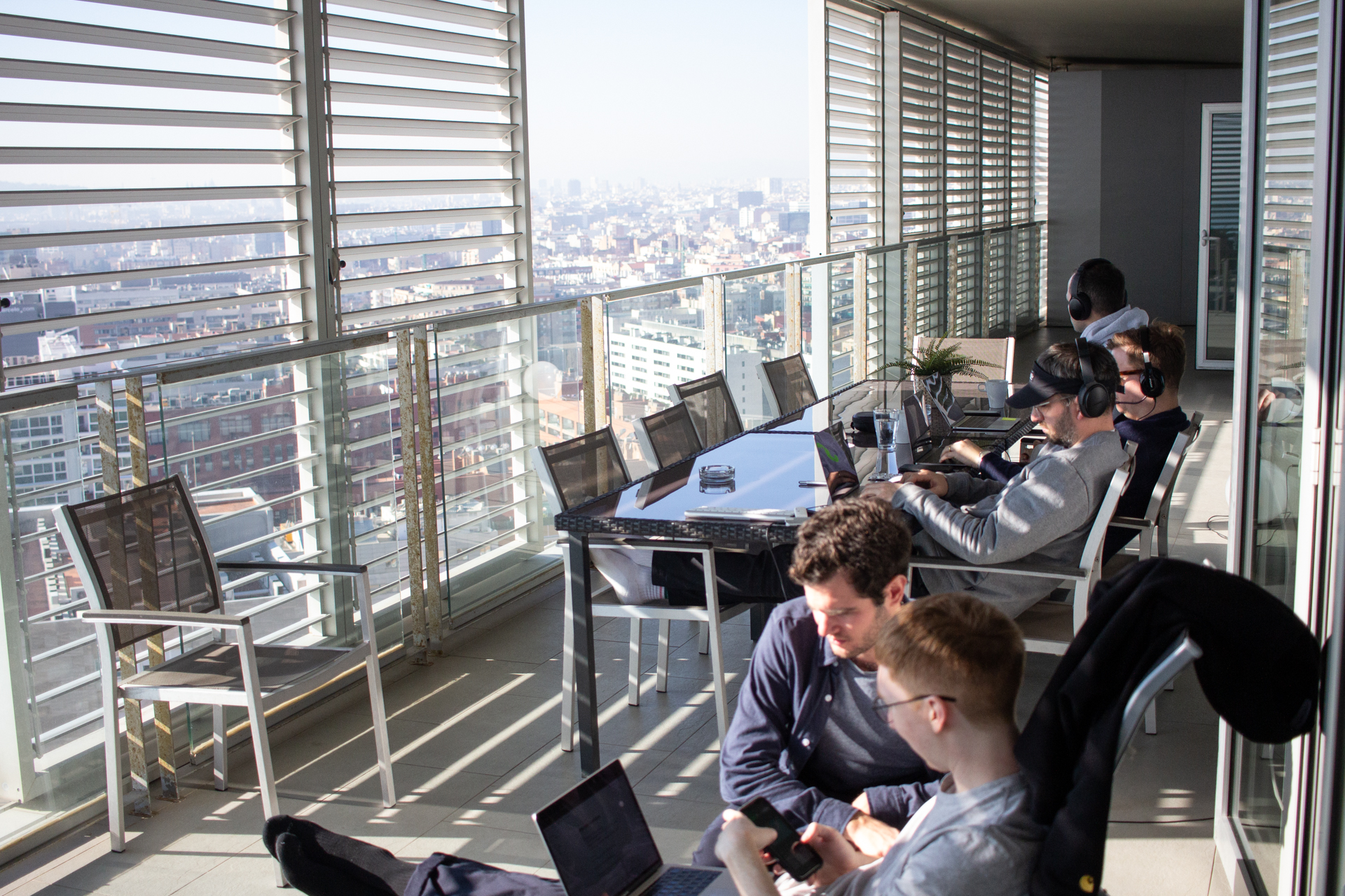 A team at work on laptops on a sunny balcony in Barcelona