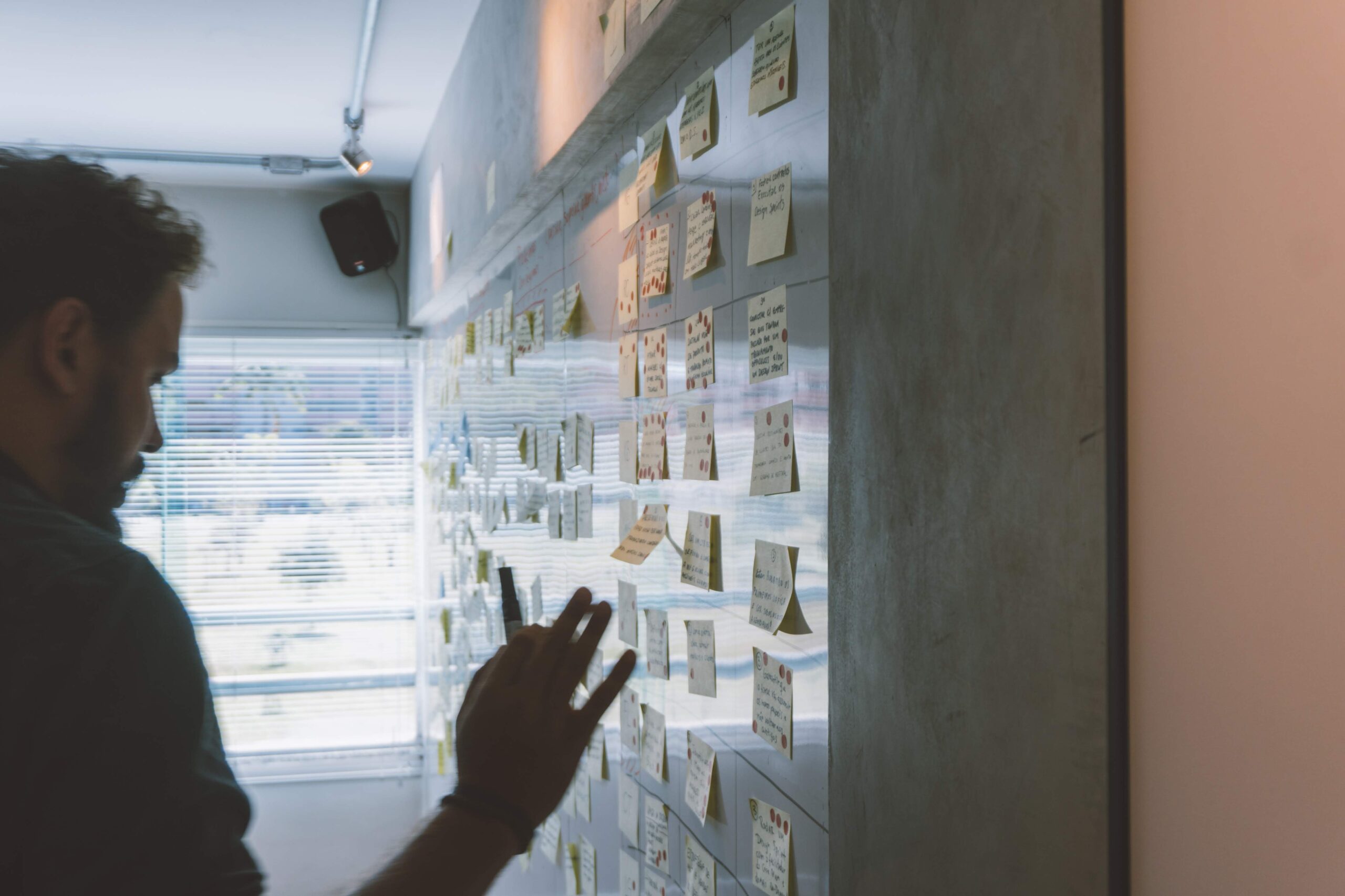 A team examine post it notes on a wall as part of a design sprint 2.0