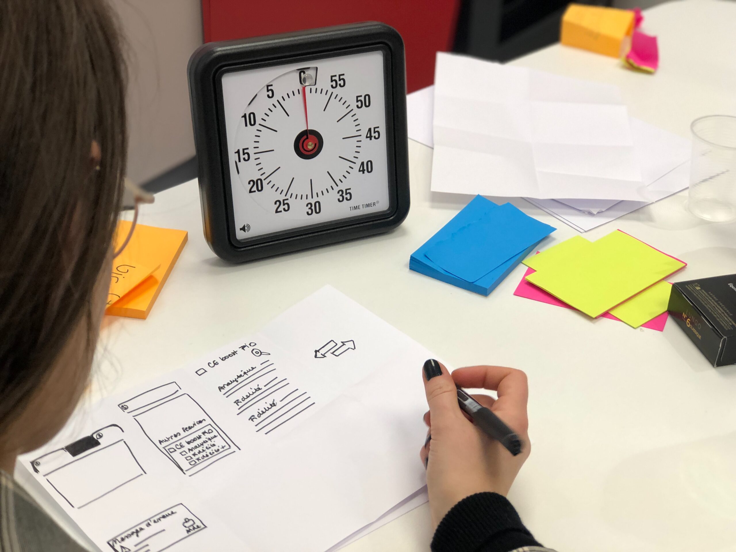 A team works during a design sprint with a clock in front of them