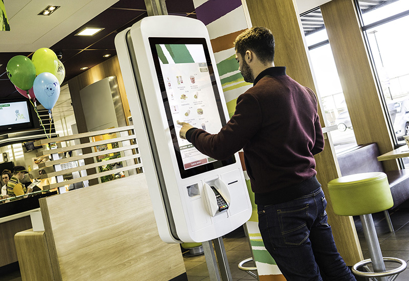 A customer interacts with a McDonalds self serve kiosk